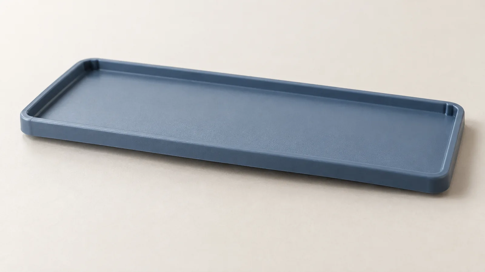 Petit capot en plastique bleu ardoise dont le bord long présente un léger cintrage.