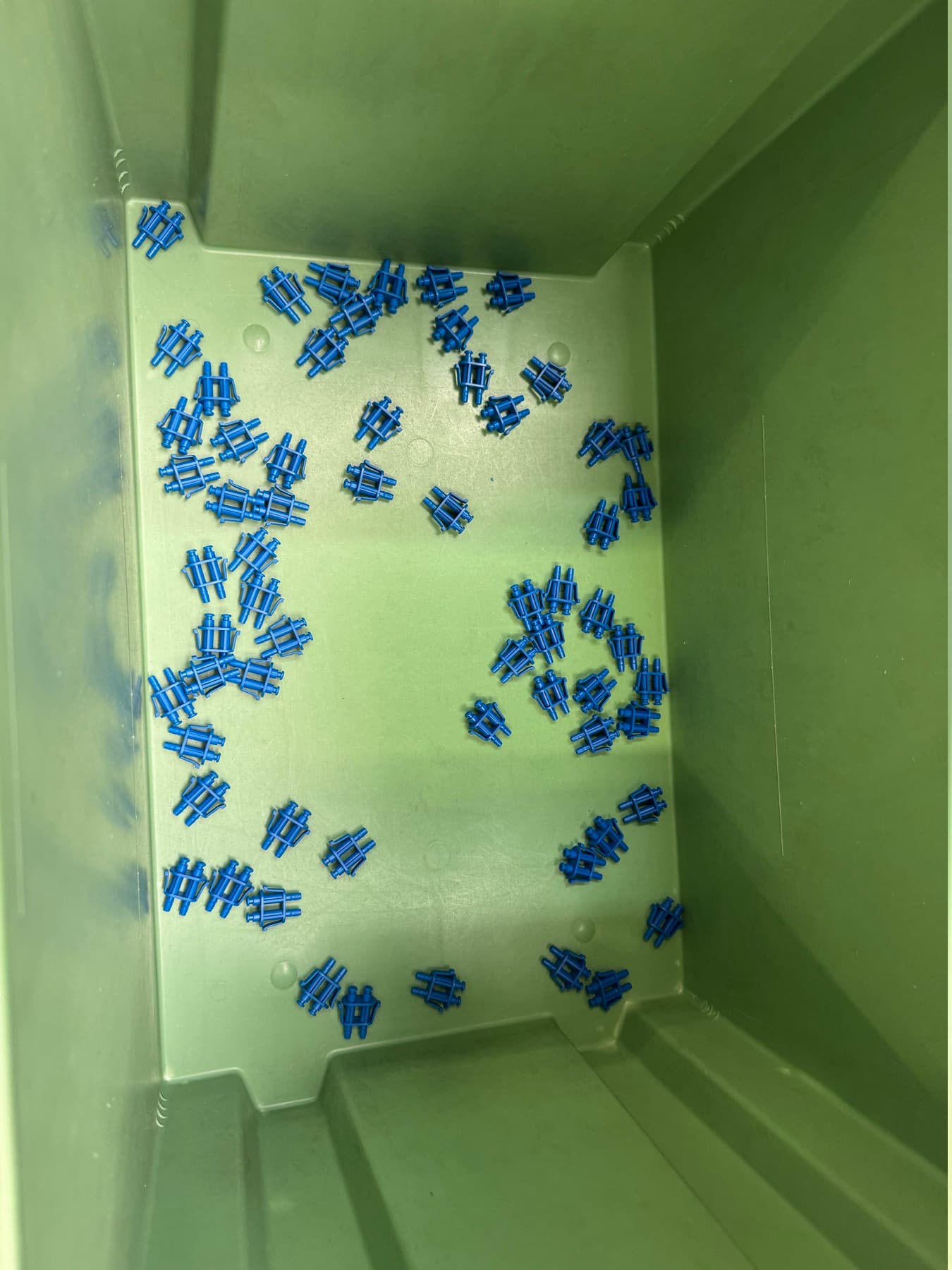 Pièces plastiques bleues en vrac dans un bac