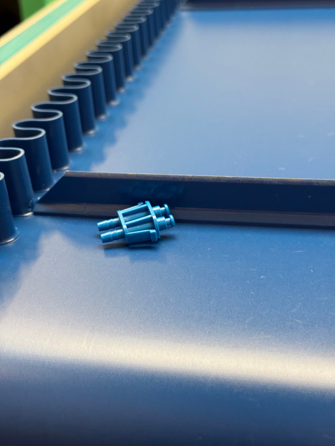Raccord plastique bleu en bout de convoyeur d’atelier, à la sortie de la presse