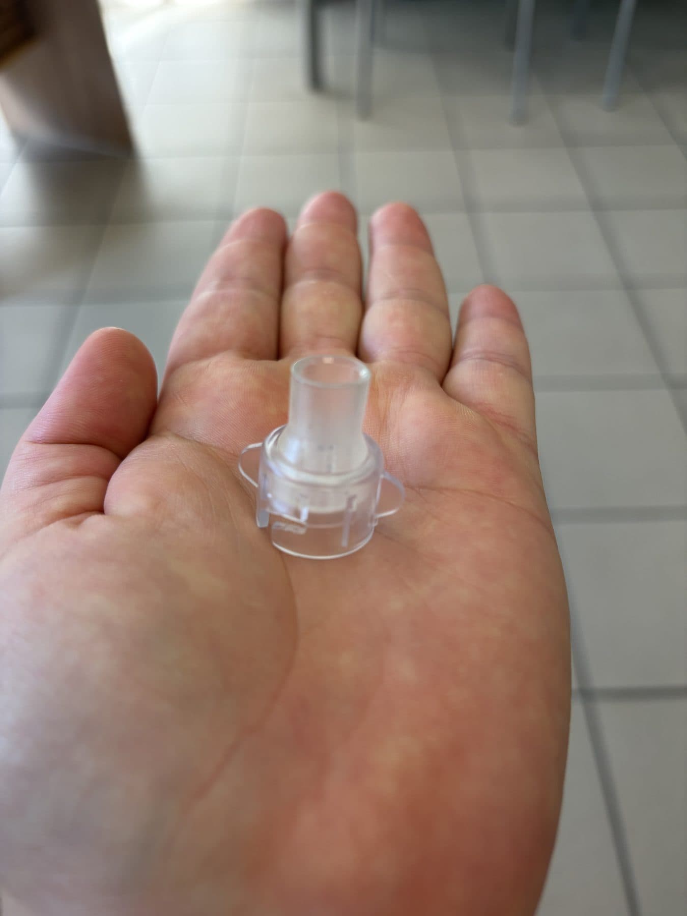 Raccord plastique transparent à ailettes de préhension, tenu dans la paume